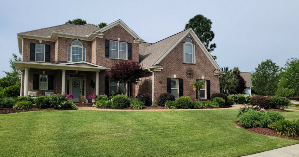 Beautifully maintained residential lawn with neatly trimmed grass, manicured shrubs, and vibrant landscaping, showcasing Home and Lawn Hero’s professional lawn care services in Wilmington, NC.